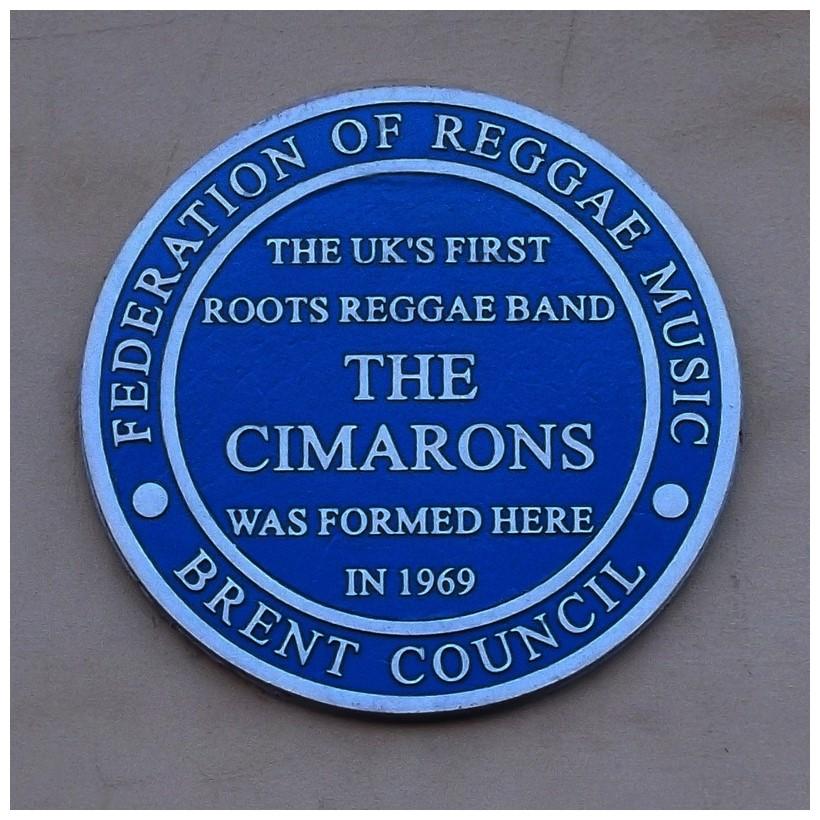 colour photograph of a blue plaque reading, ‘The UK’s first roots reggae band THE CIMARONS was formed here in 1969’, surrounded by text reading, ‘Federation of Reggae Music’ and also ‘Brent Council’.