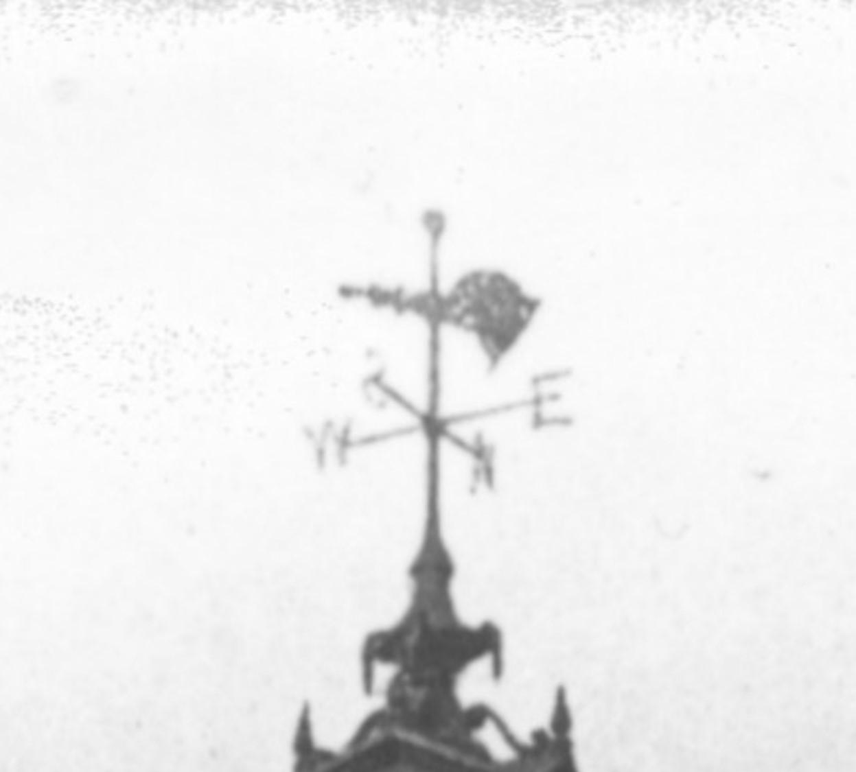 Close up of a section of a black and white photograph showing the lamps on the sides of an historic clock.