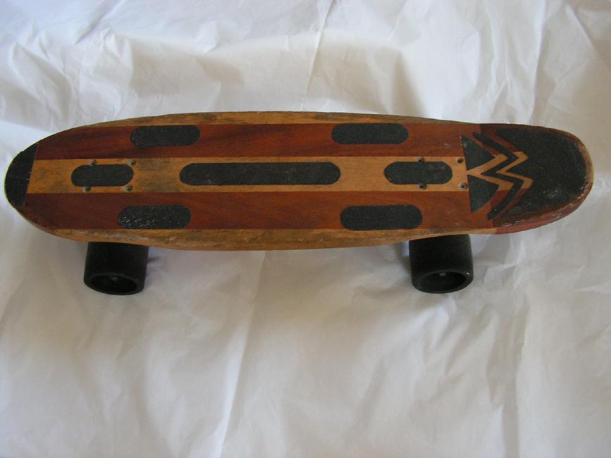 Colour photograph of a small wooden skateboard on a white background